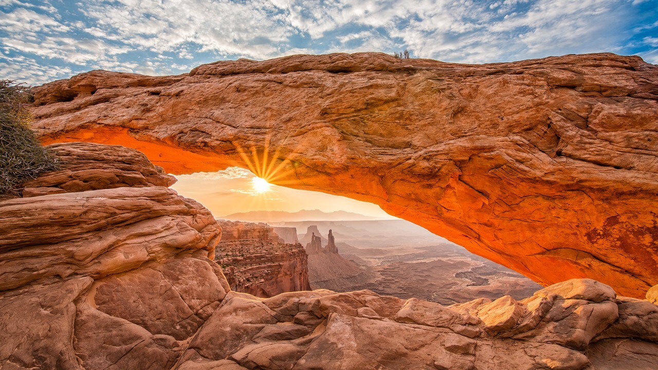 The morning sun peaks illuminates Mesa Arch in Canyonlands National Park.