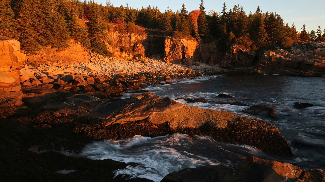 The coastline is bathed in warm light as the sun rises.