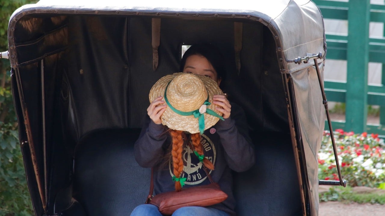 A tourist tries on Anne's hat at Green Gables Heritage Place.