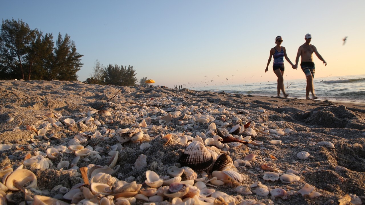 A couple walks along Captiva Beach.