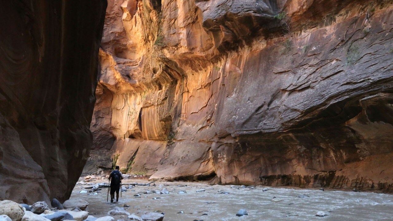 A hiker walks through The Narrows.