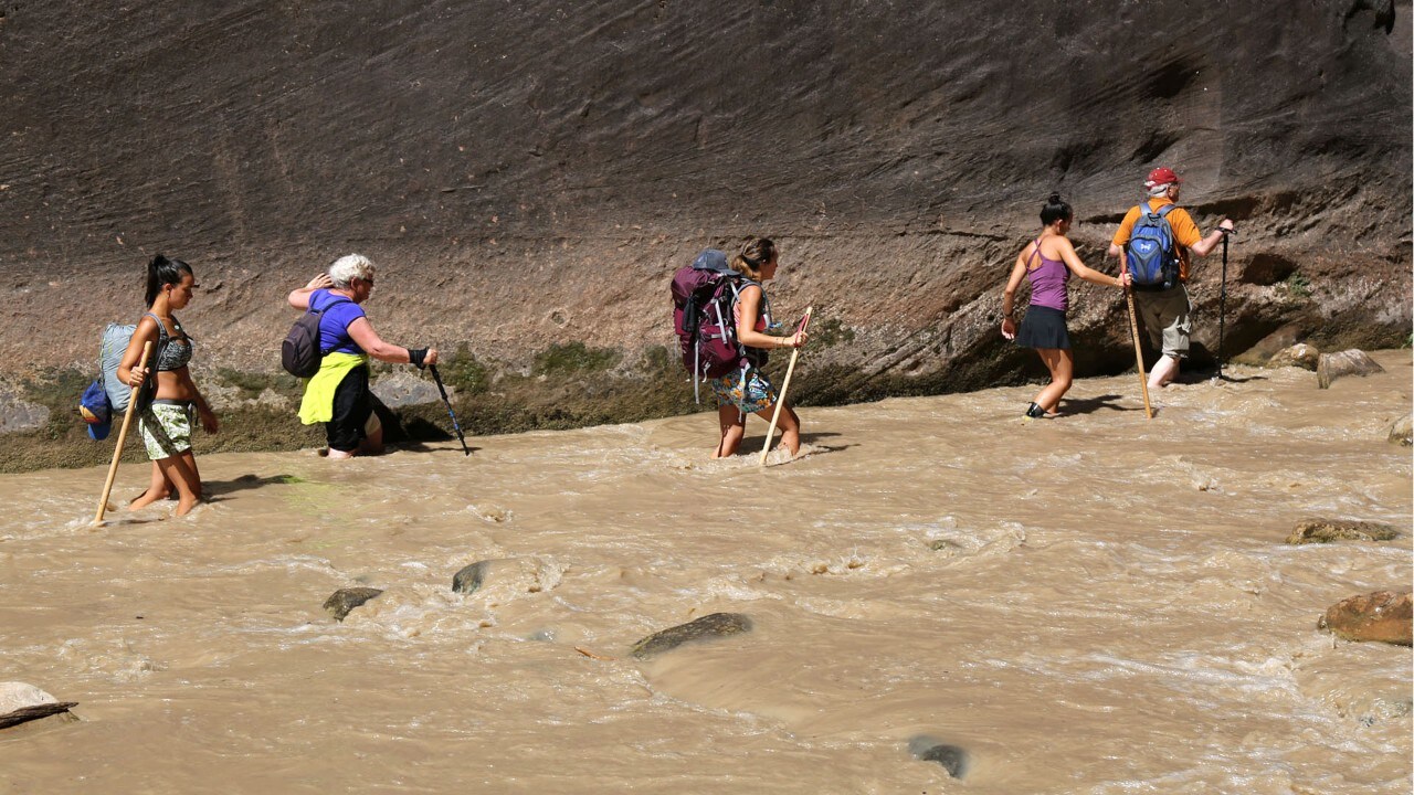 Hikers use walking sticks on a trek through The Narrows.