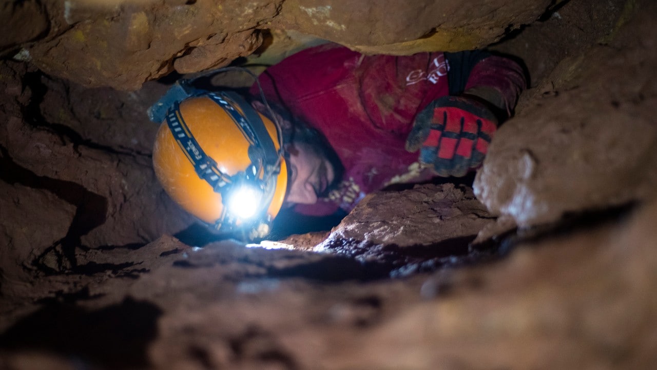 Kevin Chase squeezes through a tight section of Bookworm Alley in Rushmore Cave.