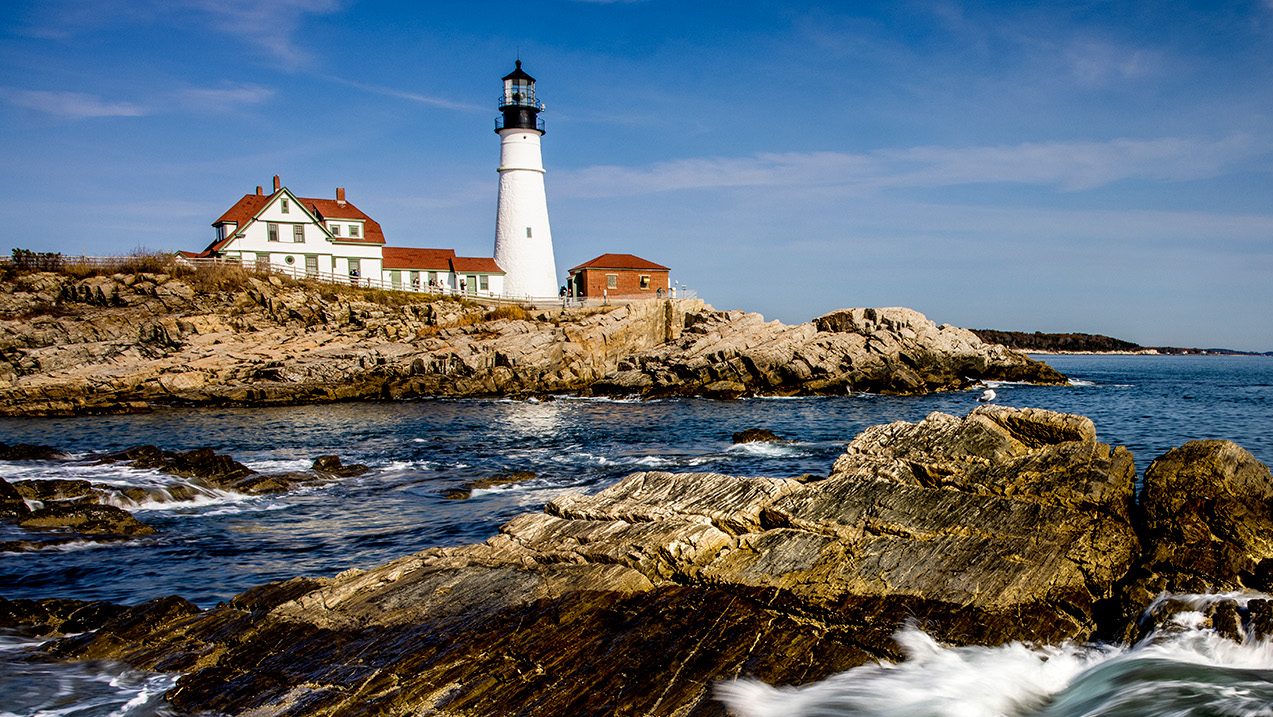 Waves crash on the rocks next to the Portland Head Light.