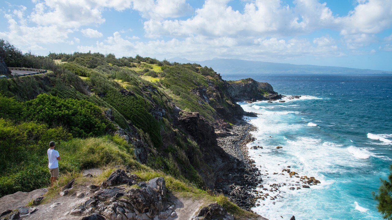 A man admires the rugged coastline along Kahekili Highway. 