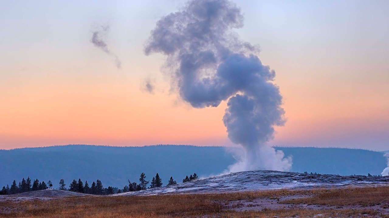 USA, Wyoming, Yellowstone National Park, Old Faithful Geyser erupting at sunset