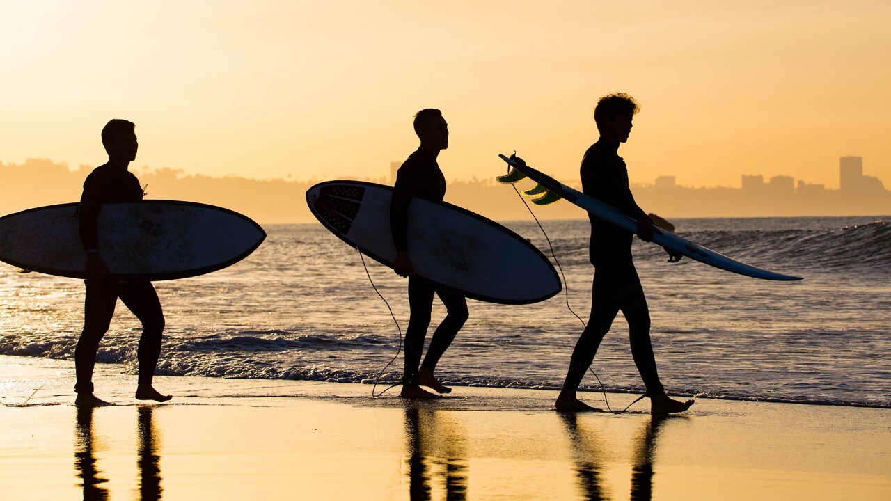 Surfers venture into the waves at Topanga Beach.