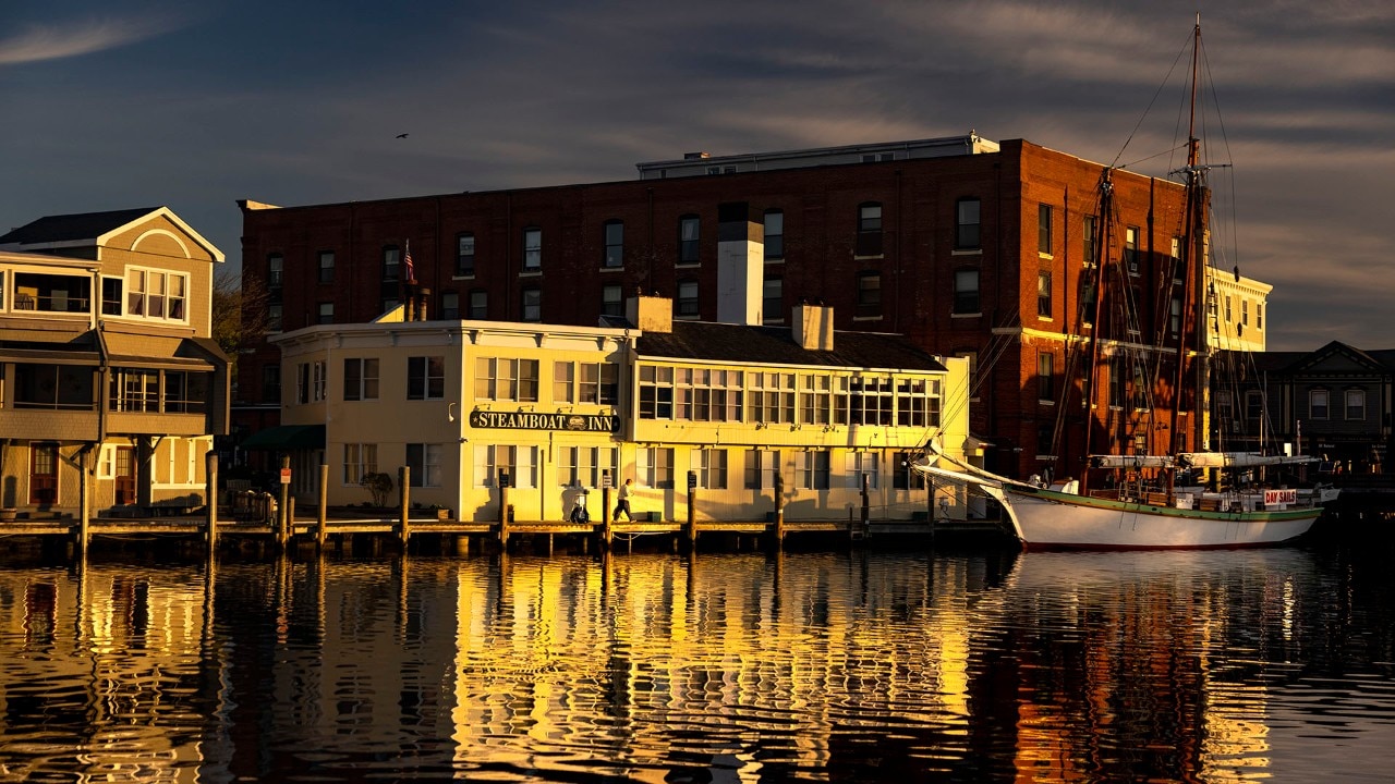 The Steamboat Inn and the sailboat Argia light up during the sunrise over the Mystic River.