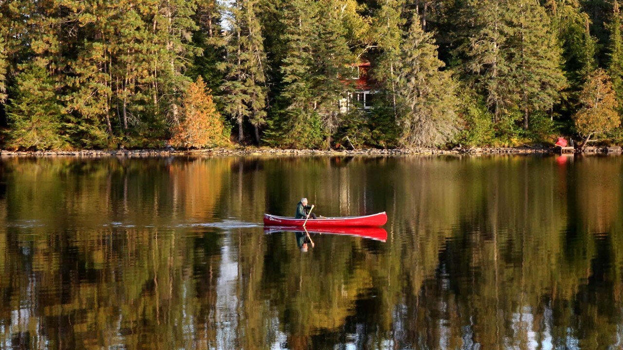 A man canoes past Killarney Lodge.