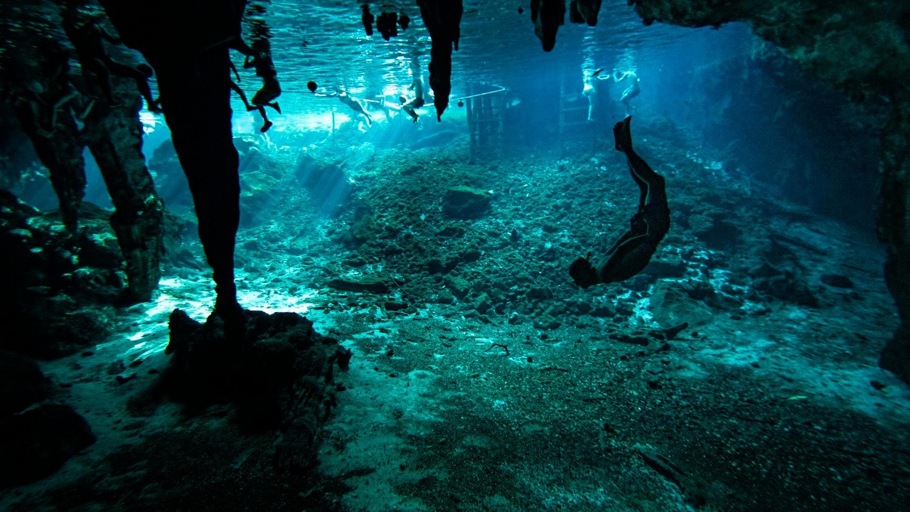 A man swims in the water at Gran Cenote in Tulum.