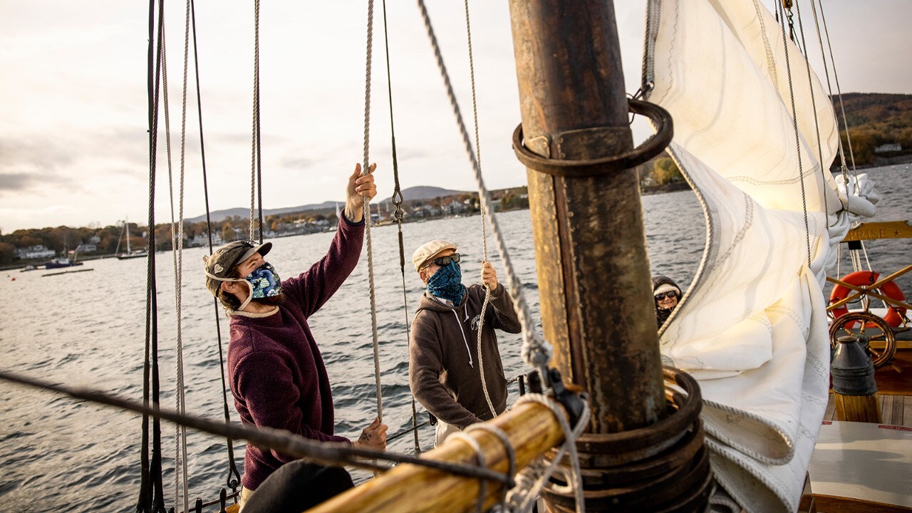 Sailors on the Schooner Suprise hoist the main sail as it makes its way out of Camden harbor.