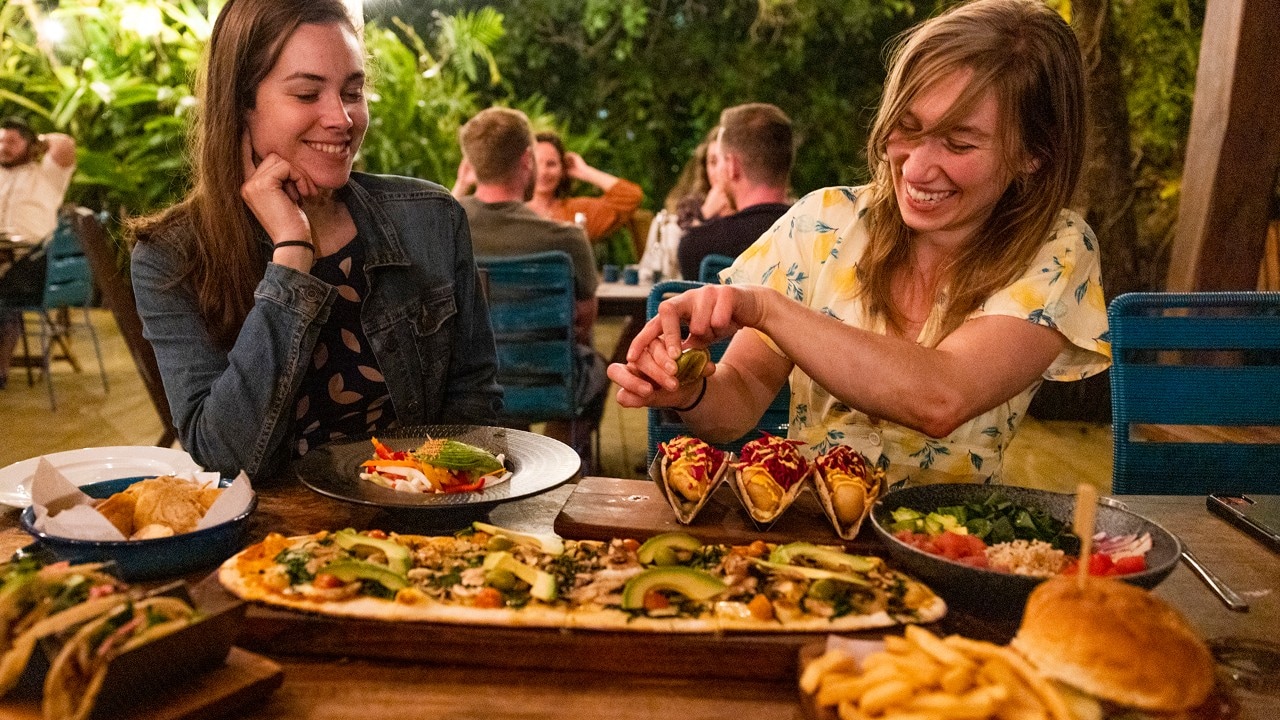 Kassondra watches Corey squeeze lime juice on tacos at La Playita restaurant in Bacalar.