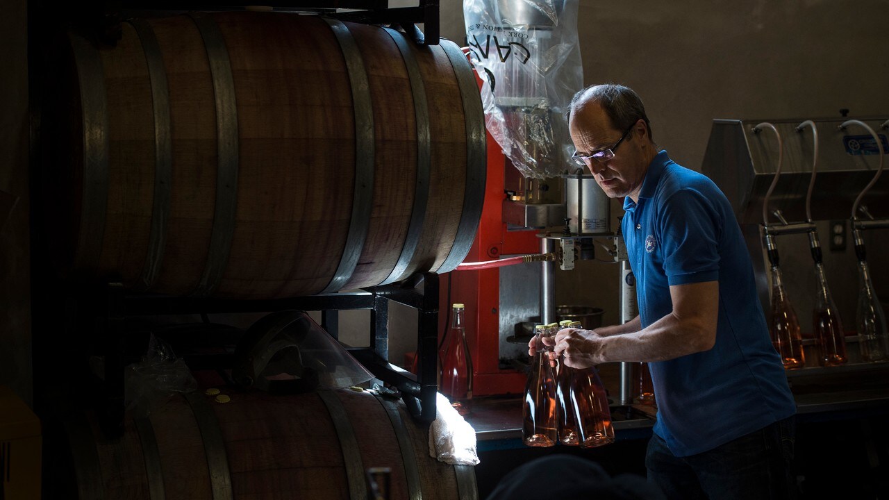 Bruce Ewert fills bottles at L'Acadie Vineyards.