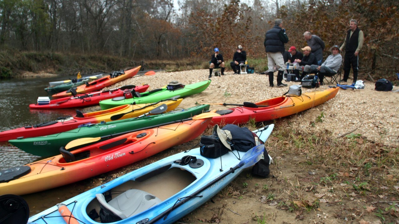 The group stops for a lunch break along a river bank.