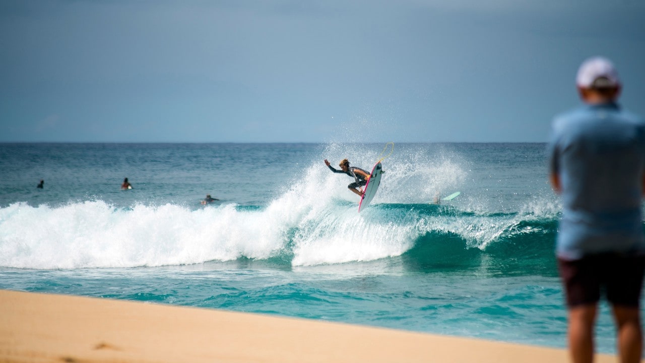 A surfer launches himself above the waves at the North Shore. 